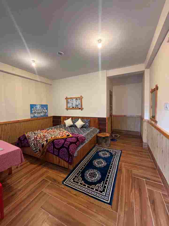 Interior of a deluxe hotel room in Tosh with a king-size bed and wooden flooring
